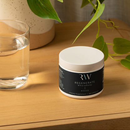 Container of Mood on a warm wooden nightstand beside a glass of water, framed by a potted plant.